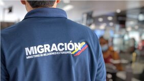 Hombre dando la espalda con logo de Migración Colombia en su espalda